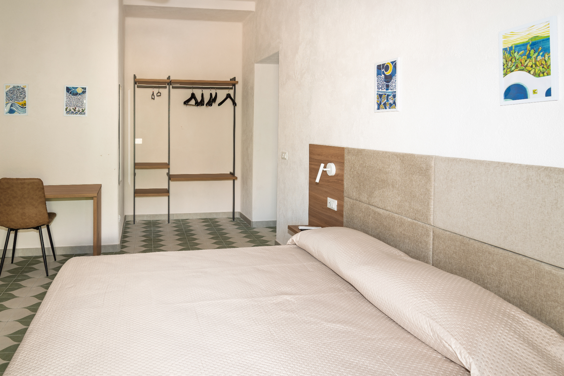 Camera Vasame con letto matrimoniale, guardaroba aperto e stampe artistiche